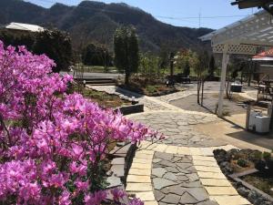 um jardim com flores roxas e um passadiço de pedra em Shinshu Wakaho Gibier B&B em Nagano