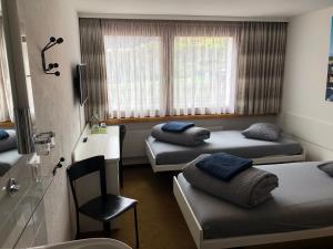 a hospital room with three beds and a chair at Catrina Lodge in Disentis