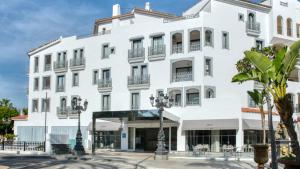 a white building with balconies and palm trees at Boutique Hotel B51 in Marbella