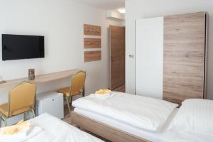 a room with two beds and a desk and a tv at Vivien Szálló in Szeged