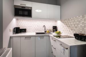 a white kitchen with white cabinets and a sink at Apartamenty Silence Baltic Glamour in Pobierowo
