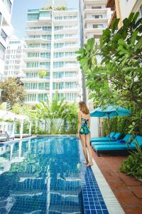 a woman in a bikini standing next to a swimming pool at Home Chic Hotel in Phnom Penh