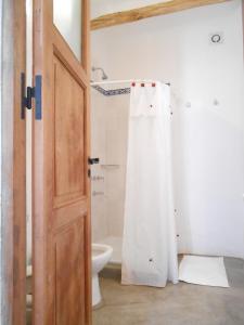 y baño con aseo y cortina de ducha. en Hosteria Villa Cardon en Cachí