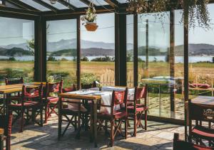a dining room with tables and chairs and windows at Torre di Baratti Bio Resort in Populonia