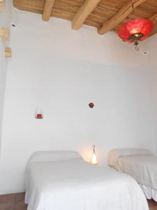 two beds in a white room with a ceiling at Hosteria Villa Cardon in Cachí
