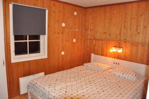 Un dormitorio con una cama con paredes de madera y una ventana en Stuga 5 Varmland en Torsby