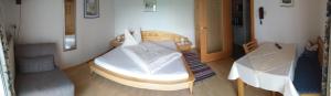 ein Schlafzimmer mit einem weißen Bett und einem Tisch in der Unterkunft Pension Waldhof in Koppl