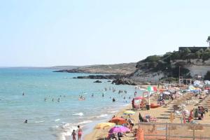 a beach with a lot of people in the water at La Maiolica in Noto Marina