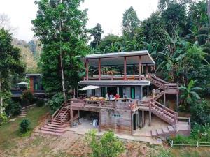 a house with a large deck with people on it at Rai Phusaitran ไร่ภูสายธาร in Mae Taeng