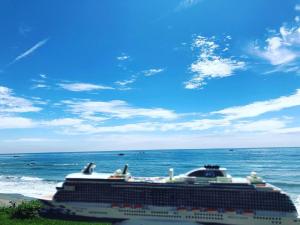 a cruise ship on the beach with the ocean at Guesthouse High Wave in Yanliau