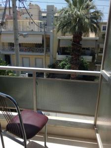 uma cadeira sentada numa varanda com uma palmeira em Omiros em Piraeus