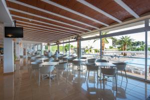 um restaurante com mesas e cadeiras e uma piscina em Hotel Caribe em Es Cana