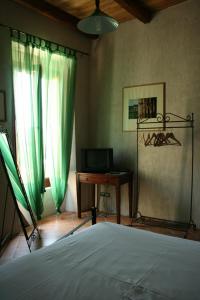 トルキアーラにあるRosacanina B&Bのベッドルーム1室(ベッド1台、デスク、緑のカーテン付)