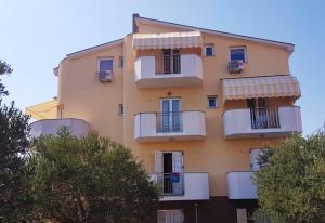 ein hohes gelbes Gebäude mit Balkonen und Bäumen in der Unterkunft Apartmani Lili in Sukošan