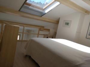 a bedroom with a white bed with a skylight at La Forge in Signes
