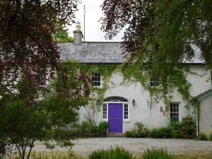 een wit huis met een paarse deur bij The Coachhouse @ Kingsfort House in Ballintogher