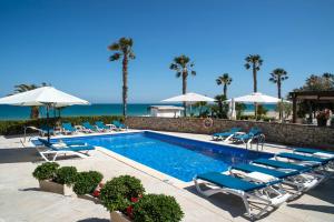 una piscina con tumbonas y el océano en Cala Cristal by Pierre & Vacances Premium, en Miami Platja