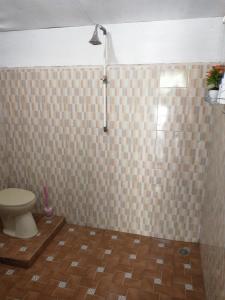 ein Bad mit einem WC und einer gefliesten Wand in der Unterkunft Pondok Oma II in Lasikin