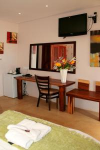 Habitación con escritorio y mesa con un jarrón de flores. en Cest Si Bon Hotel en Otjiwarongo