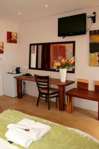 a room with a desk and a table with a vase of flowers at Cest Si Bon Hotel in Otjiwarongo