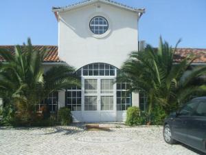a white house with palm trees in front of it at Monte dos Duques in Santo Estêvão