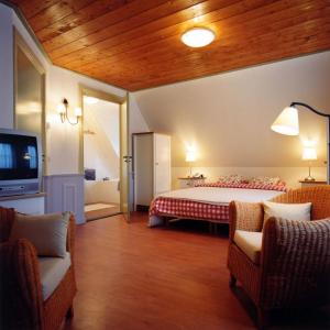 a bedroom with a bed and two chairs and a tv at Hotel Vesting Bourtange in Bourtange