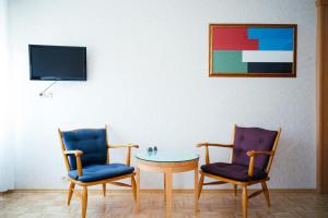 two chairs and a table in a room with a tv at Hotel Am Brillantengrund in Vienna