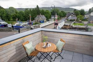 a table and chairs on a balcony overlooking a river at Lock Chambers, Caledonian Canal Centre in Fort Augustus
