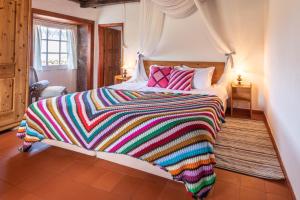 a large bed with a colorful blanket on it at Aldeia da Cuada in Faja Grande