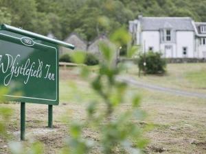 een groen bord in een veld met een huis op de achtergrond bij Whistlefield Inn in Dunoon