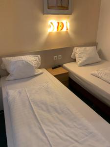 duas camas num quarto com uma luz na parede em Hotel New Fair Munich Messe em Munique