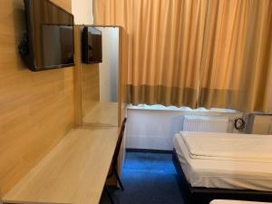 um pequeno quarto com uma cama e uma televisão em Hotel New Fair Munich Messe em Munique