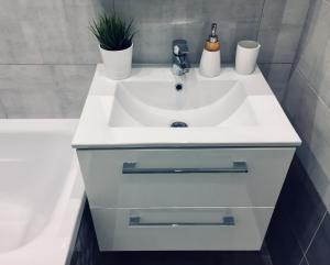 a bathroom with a white sink and a tub at Rebel Apartament in Bielsko-Biała