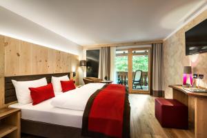 a hotel room with a large bed with red pillows at Albergo Posta Pederoa in La Valle