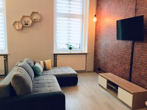 a living room with a couch and a brick wall at Rebel Apartament in Bielsko-Biała