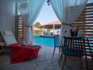 eine Terrasse mit einem Tisch, Stühlen und einem Pool in der Unterkunft Fantasy Hotel in Kolymbia