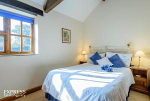 a bedroom with a white bed with blue pillows at Highgrove Barns in Craven Arms