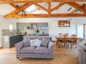 a living room with a couch and a kitchen at Apple Tree Cottage in Soulby