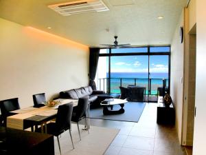 a living room with a couch and a table at Condominium NOOSA in Nago