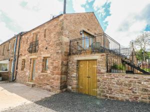 un edificio de ladrillo con puerta de madera y balcón en Apple Tree Cottage, en Soulby