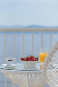 a table with a bowl of strawberries and a cup of orange juice at Greco Mare in Kavos