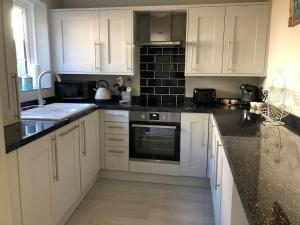 a kitchen with white cabinets and black counter tops at Boutique Townhouse in Christchurch Dorset in Christchurch