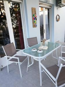 a glass table and chairs on a patio at Delikos House in Limenaria