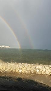a rainbow over the water with a group of rocks at Apartmani Lili in Sukošan