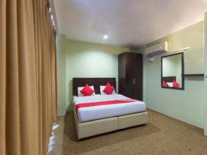 a bedroom with a bed with red pillows and a mirror at Super OYO 1102 Amani Hotel in Kampong Sungai Ramal Dalam