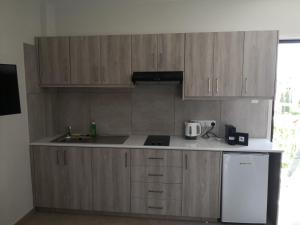 cocina con armarios de madera y nevera blanca en Proteas Mare Suites, en Protaras