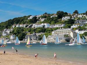 eine Gruppe von Menschen am Strand mit Segelbooten in der Unterkunft Jot Cottage in Salcombe