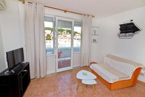 een woonkamer met een bank, een tv en een tafel bij Apartments Ive - with sea view in Tisno