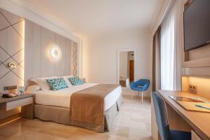 a hotel room with a bed and a desk at Grupotel Los Príncipes & Spa in Playa de Muro