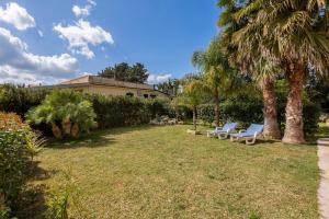une cour avec deux chaises longues et des palmiers dans l'établissement Irene's house near the sea with pool, parking & wi-fi, à Avola